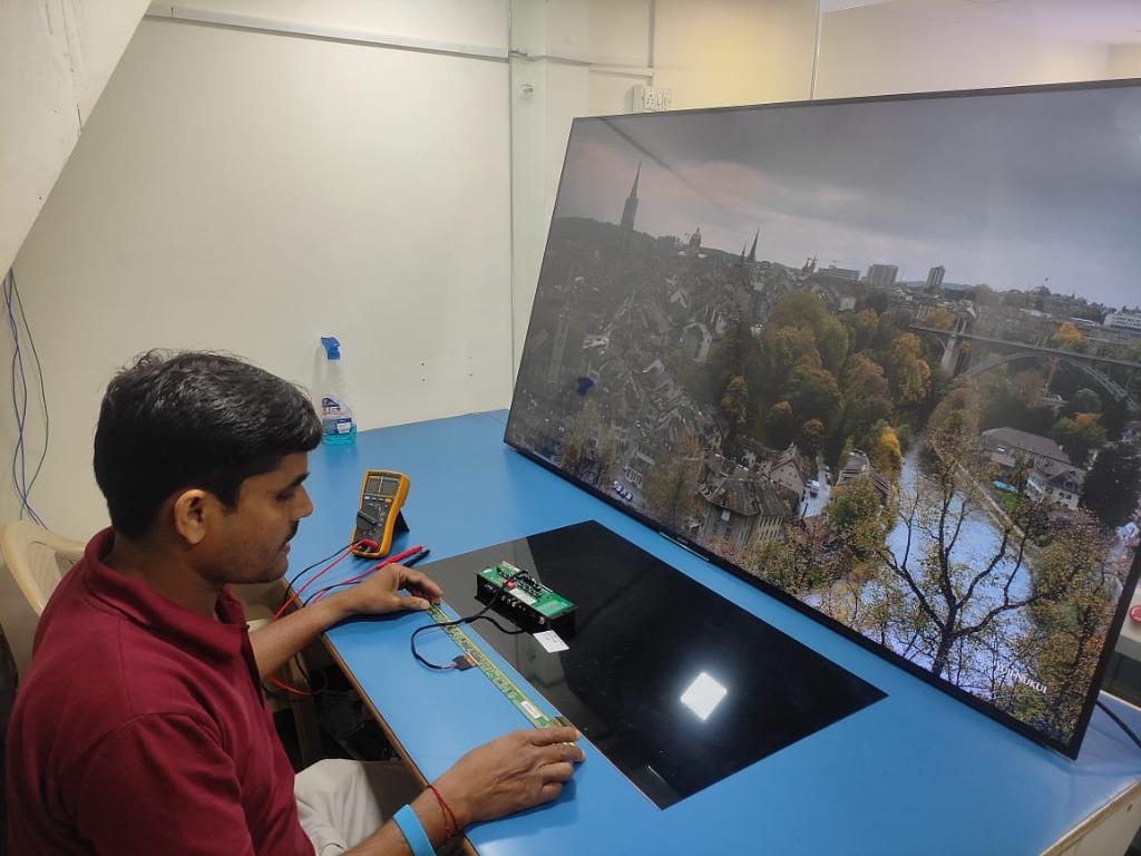 Technician testing large TV display with multimeter